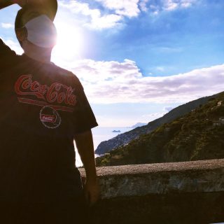 ⁣Giallo [Rosso. No! Arancione!]⠀
⠀
Vi ricordate quando il giallo e il rosso stavano a distinguere il flacone della maionese da quello del ketchup e basta? Ecco, non so voi, ma io mai e poi mai avrei pensato un giorno di ritrovarmeli a descrizione dello stato di emergenza regionale, in una pandemia globale. Personalmente, sto conducendo una vita ancora più monacale del solito. Sento odore di santità! (Scherzo, obv.). L’ultima occasione di “uscita” è questa che vedete, una foto scattata circa un mese fa, quando sono andato a far fare la revisione all’auto, prima che potessero chiudere di nuovo tutto. Un tempismo il mio degno di nota. Il giorno dopo sarebbero cominciati a catena, una serie maledetta di contagi tra i paesini della mia amata Costiera. E allo stato di insicurezza si è aggiunto, più concreto, quello di ansia. Uscire per la spesa, per andare a lavoro... il tutto con il sottofondo musicale offerto dalle sirene delle ambulanze, più frequenti del solito.⠀
⠀
Le informazioni che arrivano “dall’alto” poi, filtrate dai vari “sentito dire”, non sono mai chiare: Zona rossa! No, zona gialla! No, forse faranno una grande zona arancione! No, aspetta, forse è rossa con pois giallo ocra e un bordo esterno color bianco latte alle ginocchia che ci è venuto.⠀
Nel dubbio, mentre cerchiamo di capirci qualcosa, spero voi tutti stiate bene e che stiate uscendo lo stretto necessario, anche per non vanificare gli sforzi di chi, come il sottoscritto, resta a casa per tutelare la salute dei propri cari, se esce, porta sempre la mascherina indossata correttamente e ha fatto del disinfettante il suo nuovo profumo. Vi lascio quindi questo scorcio di pace scattato in una curva di Furore dove, dall’alto della costa, si possono ammirare tutte le sue bellezze fino ai faraglioni di Capri. Poi avanti ci sono io, che cerco di vederci chiaro, mentre indosso una maglia vintage anni ’90 arrivata da chissà dove (forse dall’America) e stretta di qualche taglia dalle sapienti mani di mia madre.